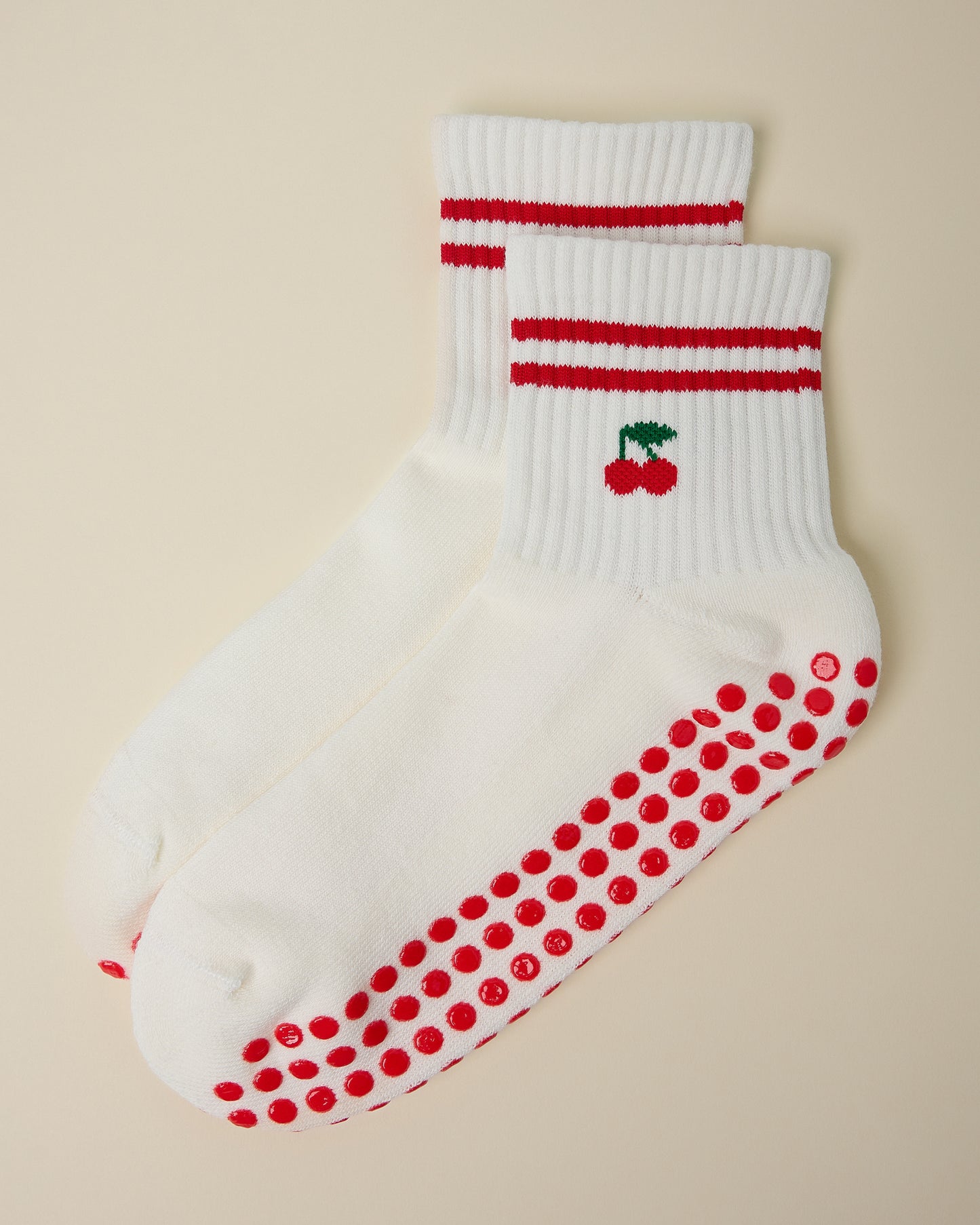 A pair of Non-Slip Quarter Crew Socks in Cherries, on a beige background.