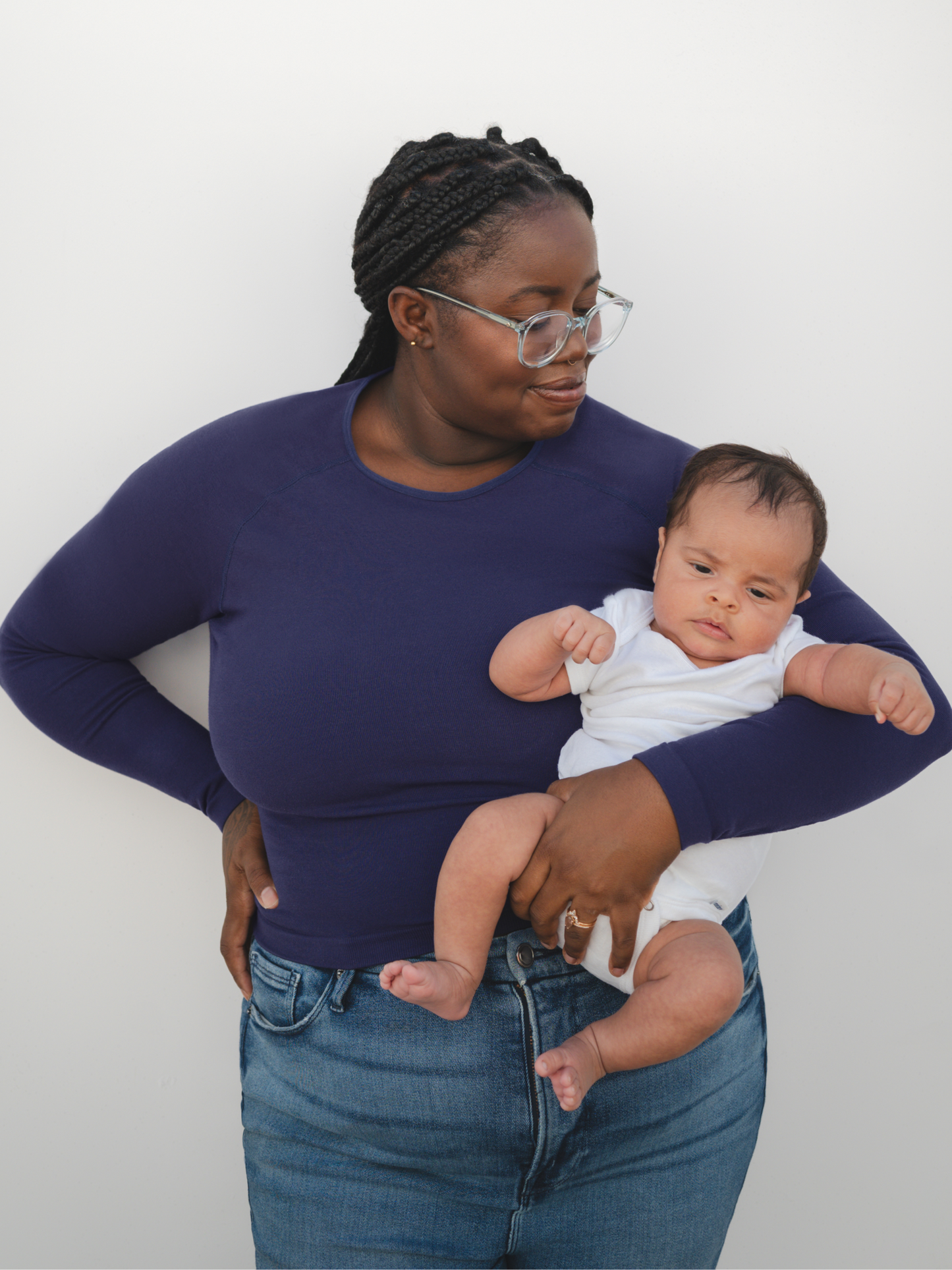 Front view of model holding baby while wearing the Sublime® Bamboo Maternity & Nursing Cropped Long Sleeve Top in Navy, paired with jeans.
@model_info:Leondra is wearing a 1X Busty.