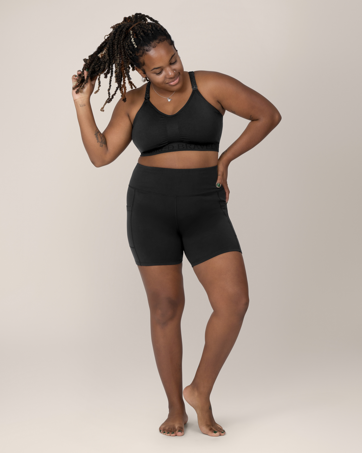 Front view of Model wearing the Stevie Active Postpartum Bike Short in Black with the Sublime Hands Free Pumping and Nursing Bra @model_info:Tonia is wearing an X-Large.