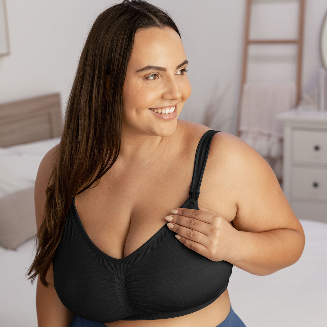 Model wearing the Sublime® Hands-Free Pumping & Nursing Bra - Super Busty in Black with her hand on the strap.