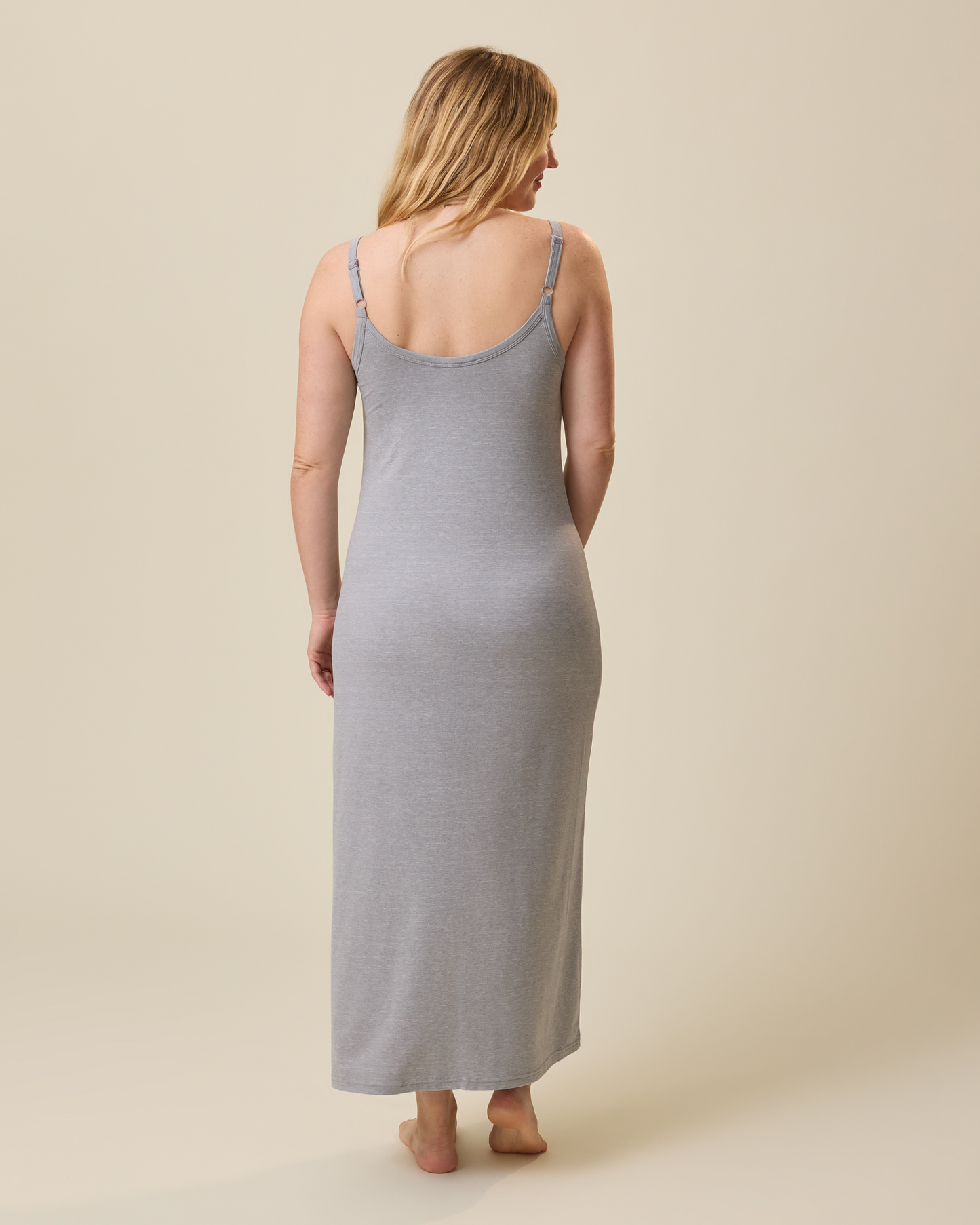 Woman wearing a gray lounge dress against a beige background