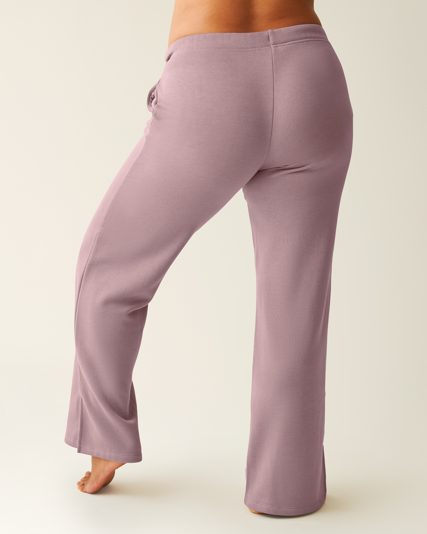 Back of woman wearing dusty mauve Cloud Fleece Sweatpant on a beige background