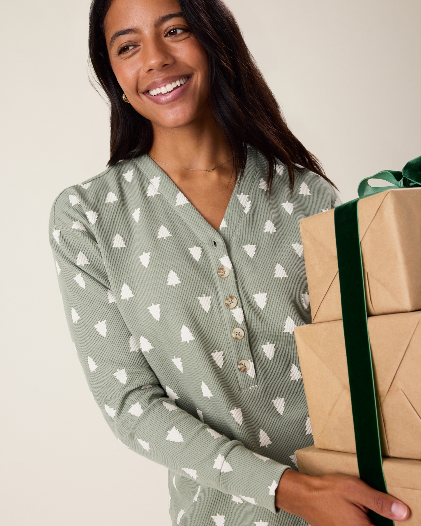 Woman wearing the top of the Waffle Maternity & Nursing Lounge Set in Sage Trees - sage green background with white tree pattern, holding wrapped gifts