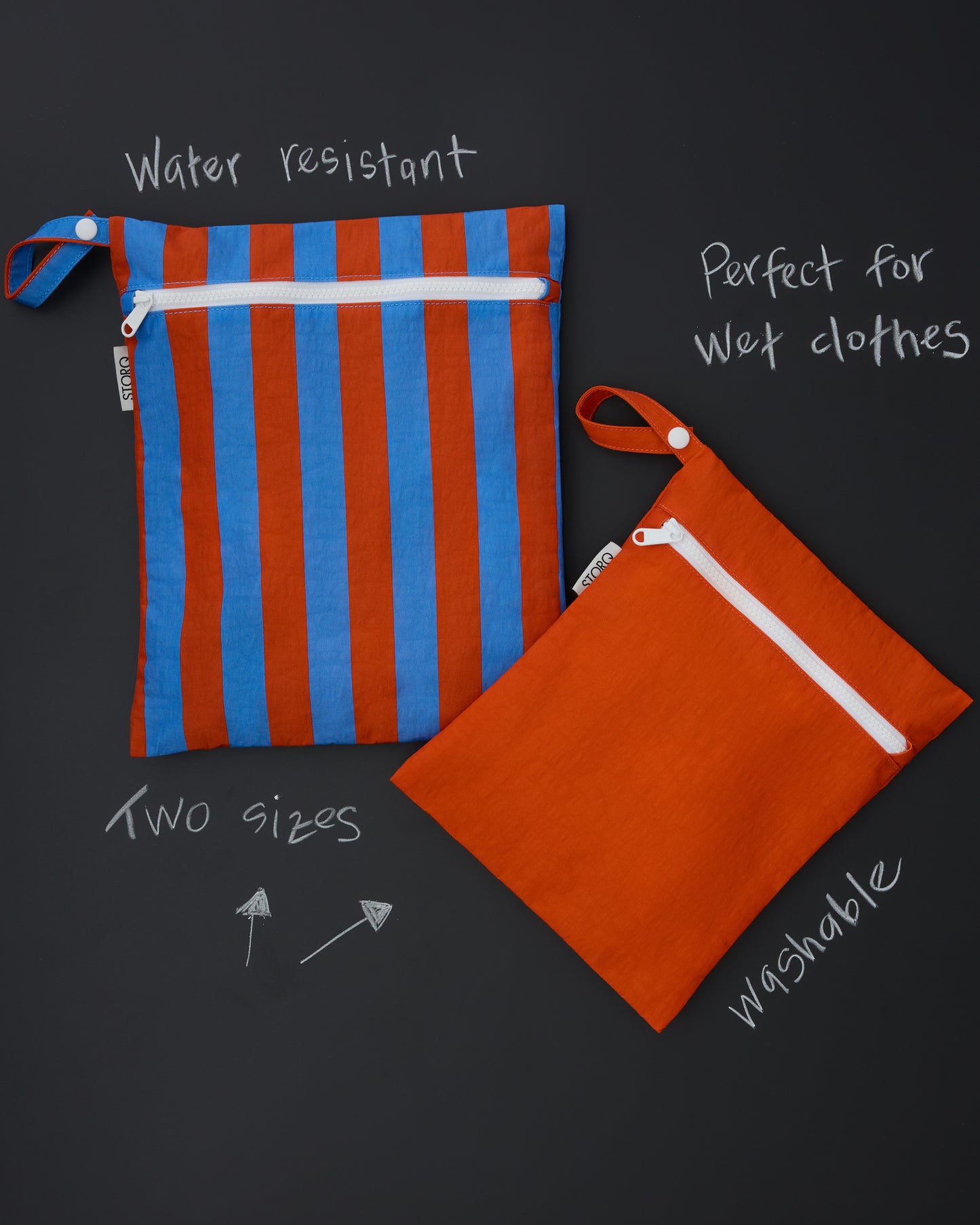 White text in chalk style calling out features of the Wet/Dry Bag Set in Blue & Rust Stripe on a black chalk board: Water resistant, Perfect for wet clothes, two sizes, washable. Images of the Wet/Dry Bag Set in Blue & Rust Stripe.