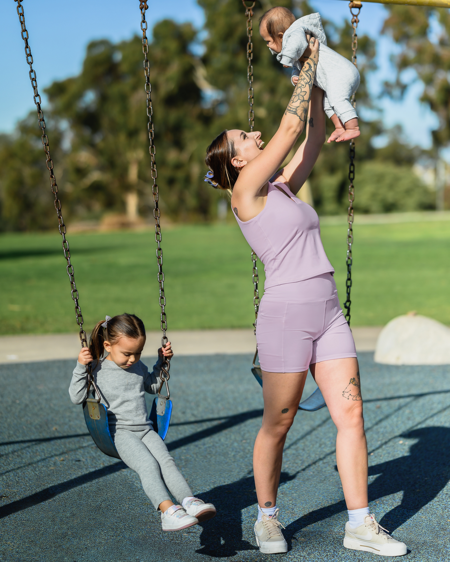 Model playing with kids outside while wearing the Stevie Active Postpartum Bike Short in Lavender Mist with the matching Wren Active V-Neck Nursing Tank Top @model_info:Anna is wearing a Small.