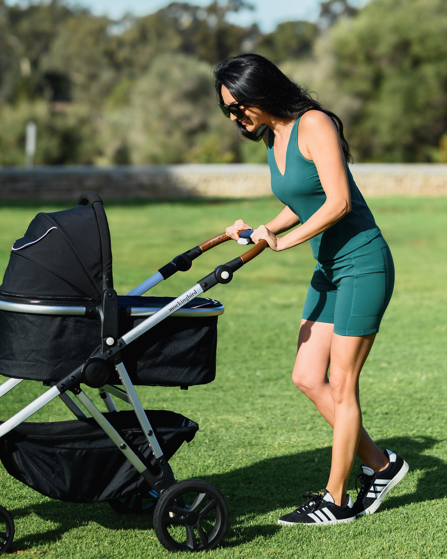Model pushing baby stroller while wearing the Wren Active V-Neck Nursing Tank Top in Teal with matching Stevie Active Postpartum Bike Short