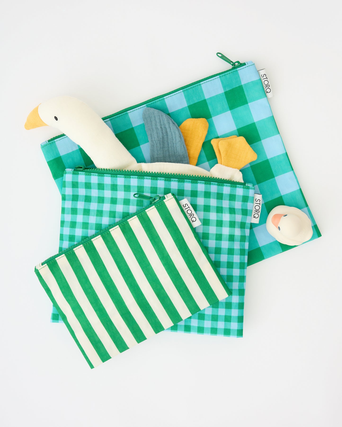 Zipper Pouch Three-Piece Set in Teal Gingham with a rubber ducky and a goose lovey sticking out of the medium sized pouch, on a beige background.