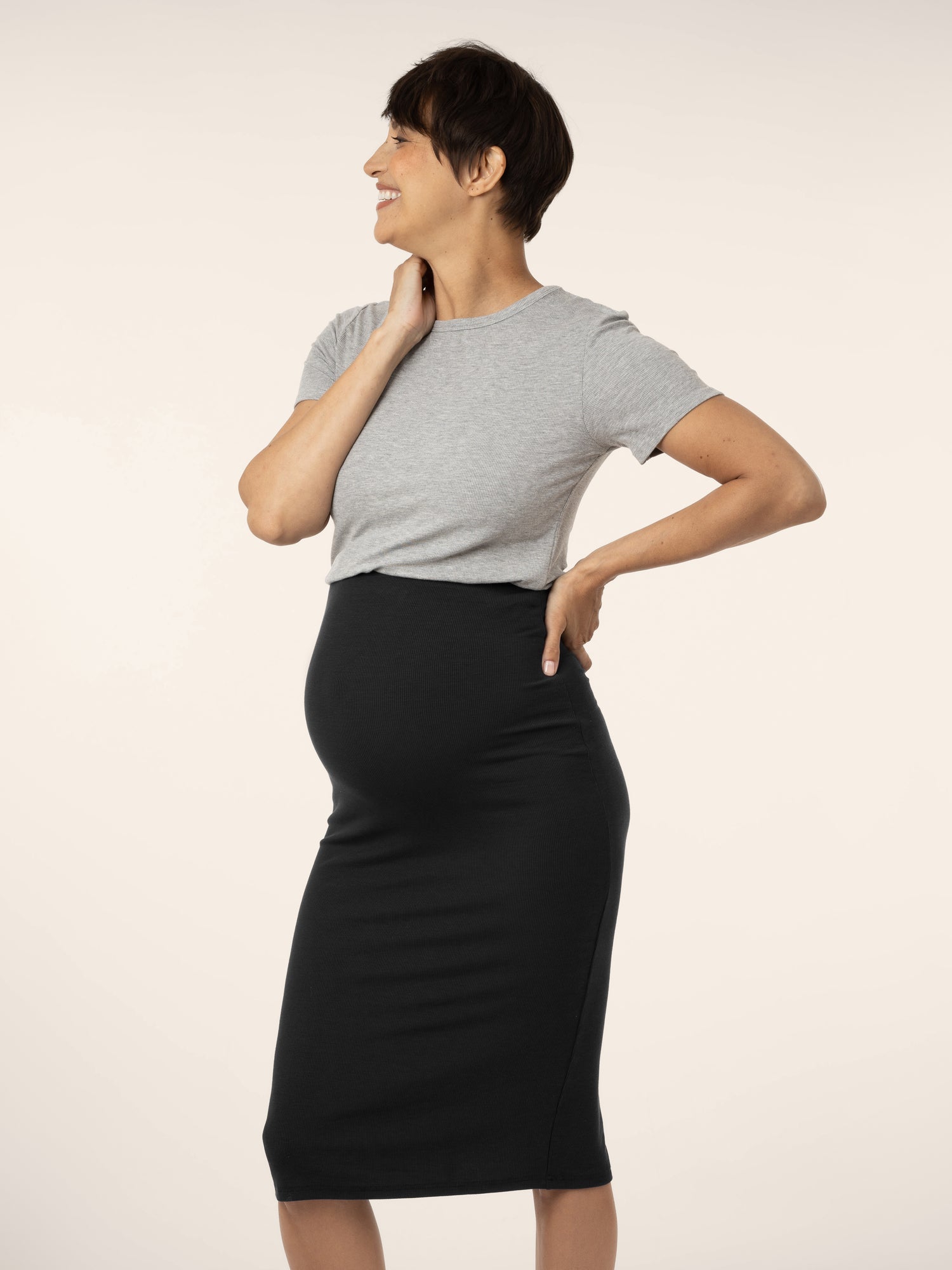 Side view of pregnant model wearing the Ribbed  Bamboo Maternity & Postpartum Midi Skirt in black