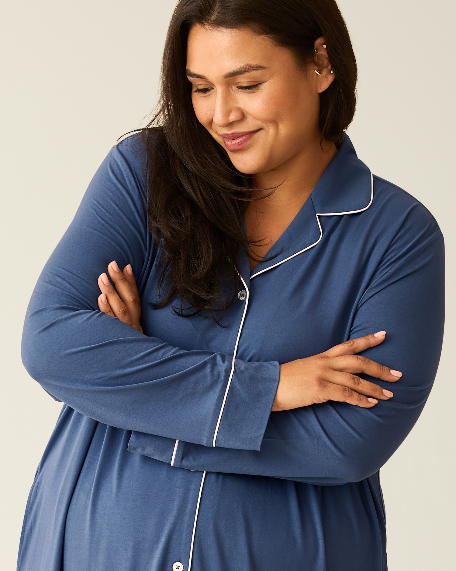 Woman wearing the Clea Bamboo Long Sleeve Sleep Shirt in slate blue with white trim on a beige background