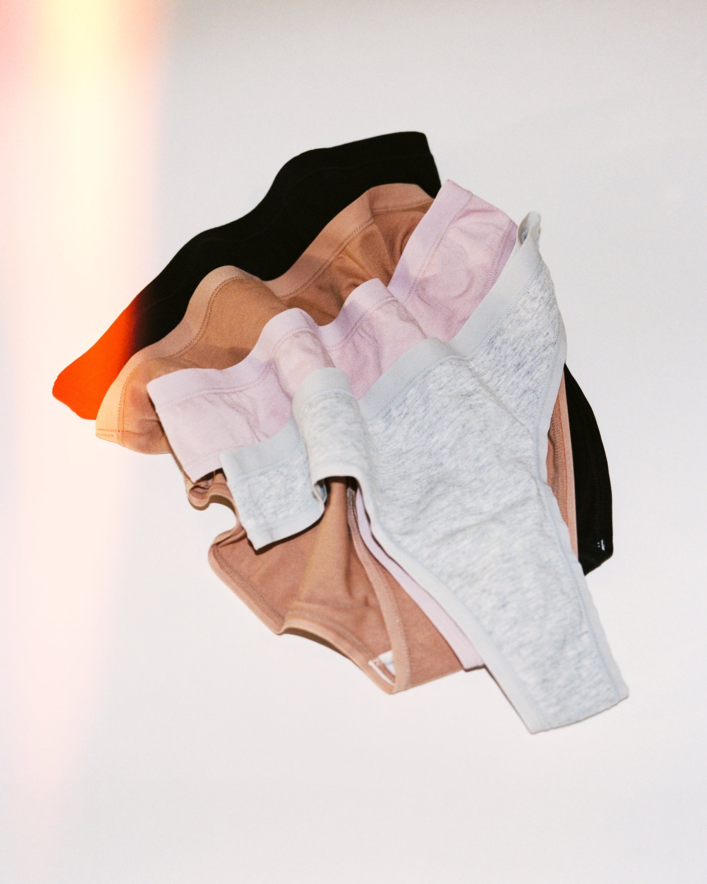 Vintage-stylized image of SoftStretch Thong, Brief and Hipster in a scrunched three-quarter view lay on a beige background.