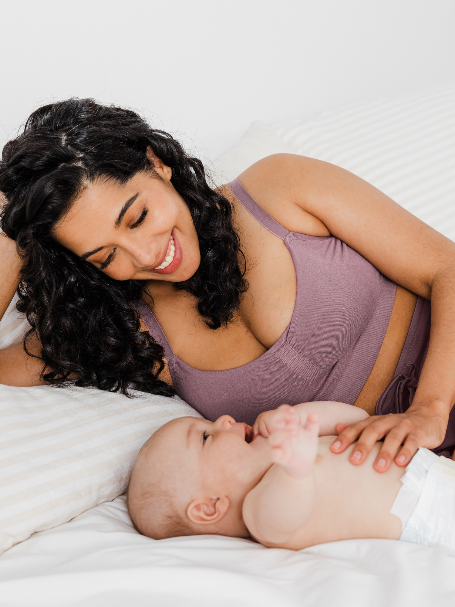 Model laying on the bed with a baby wearing the Sublime® Bamboo Hands-Free Pumping Lounge & Sleep Bra in Twilight  