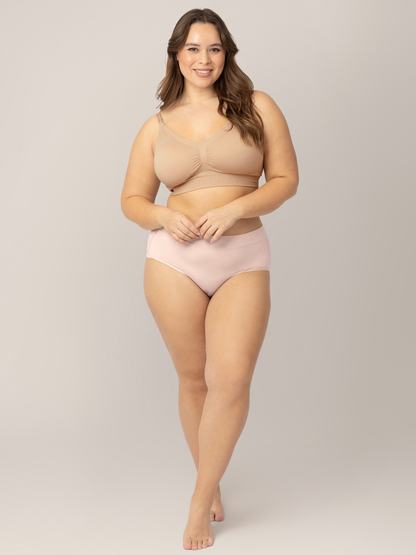 Model wearing the Grow with Me™ Maternity & Postpartum Brief in soft pink with her hands near her stomach. @model_info:Venezia is wearing a Large.