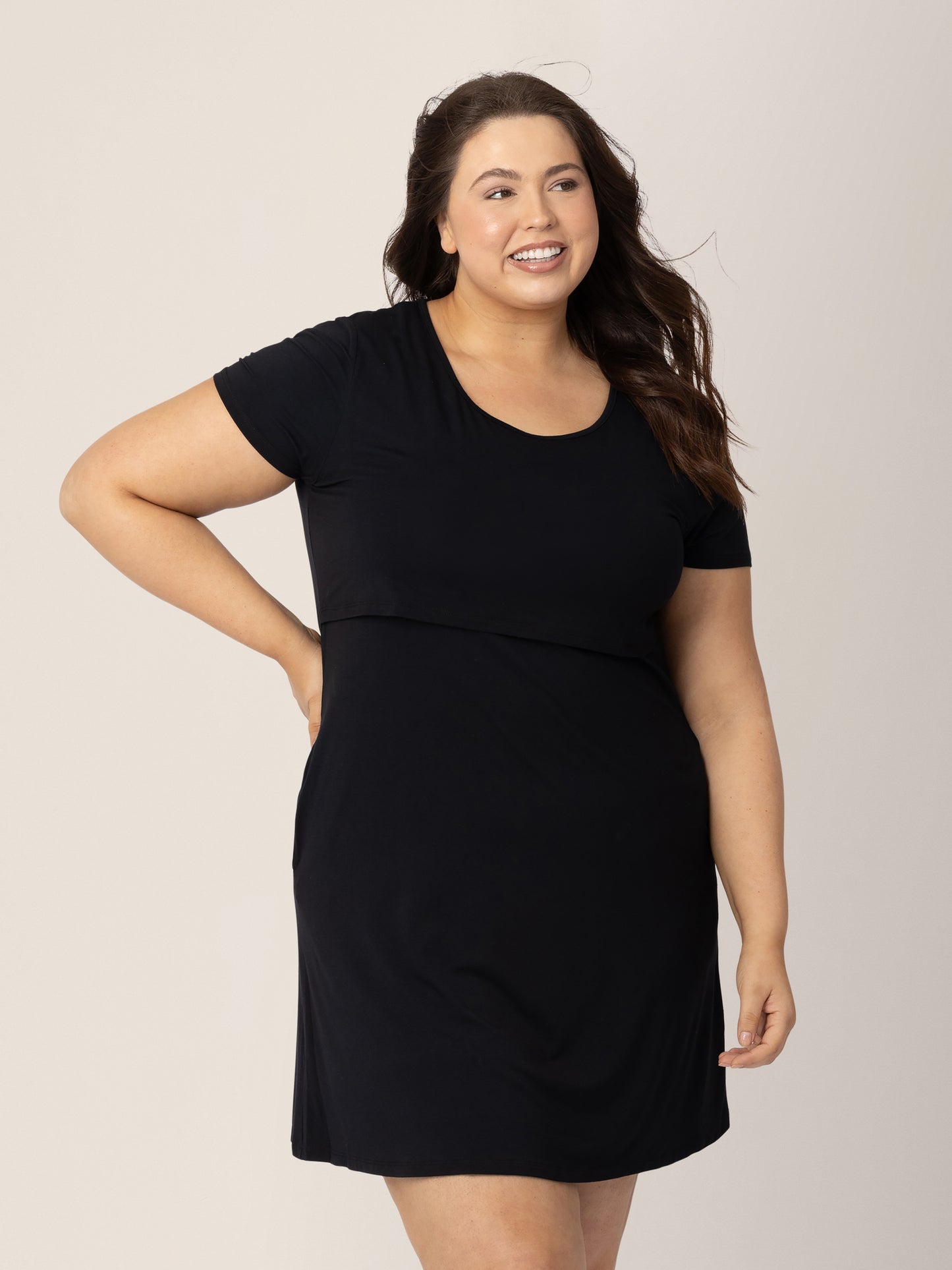 Model wearing the Eleanora Bamboo Maternity & Nursing Dress in Black with her hand on her hip. @model_info:Bailey is 5'10" and wearing an X-Large Busty.
