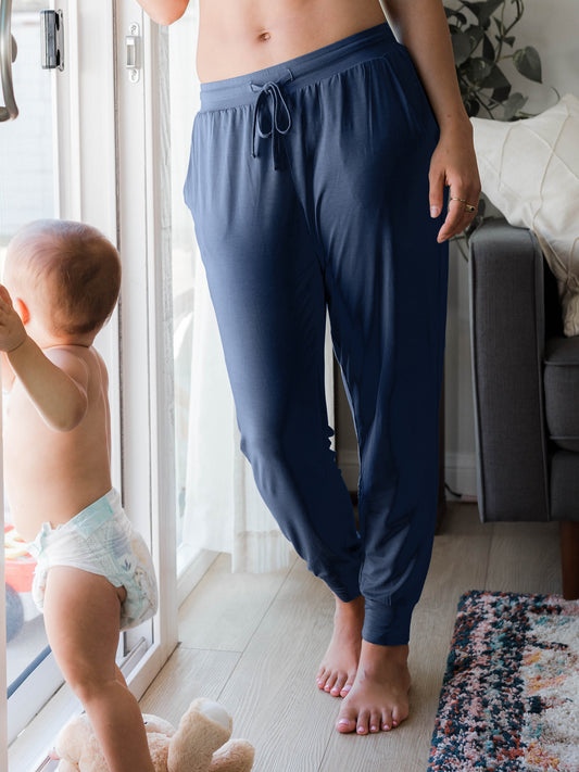 Model leaning against a sliding glass door with her baby @model_info:Arion is wearing a Small Regular.