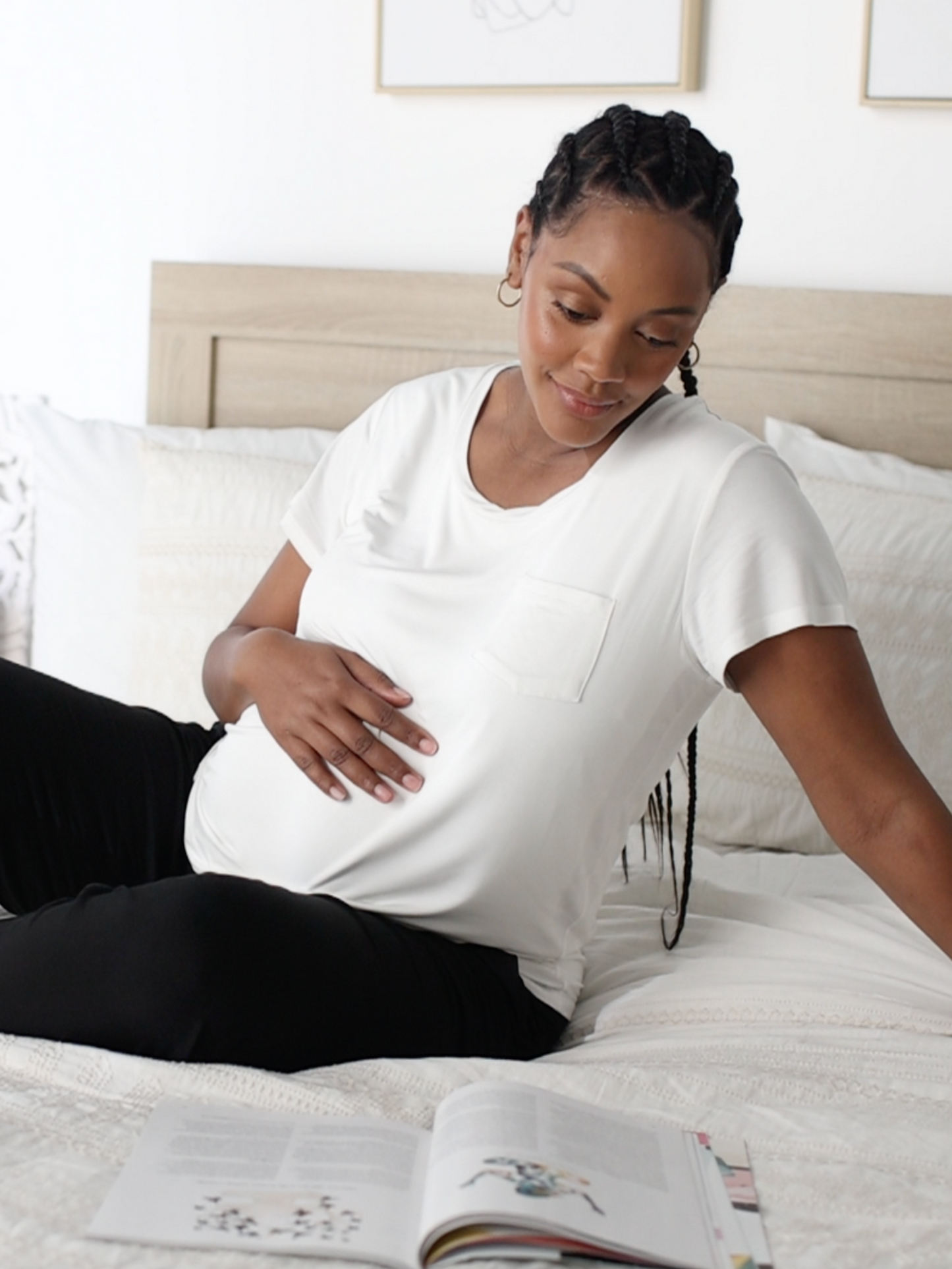 Model sitting on a bed while wearing the Everyday Maternity & Nursing T-shirt in White @model_info:Roxanne is wearing a Large.