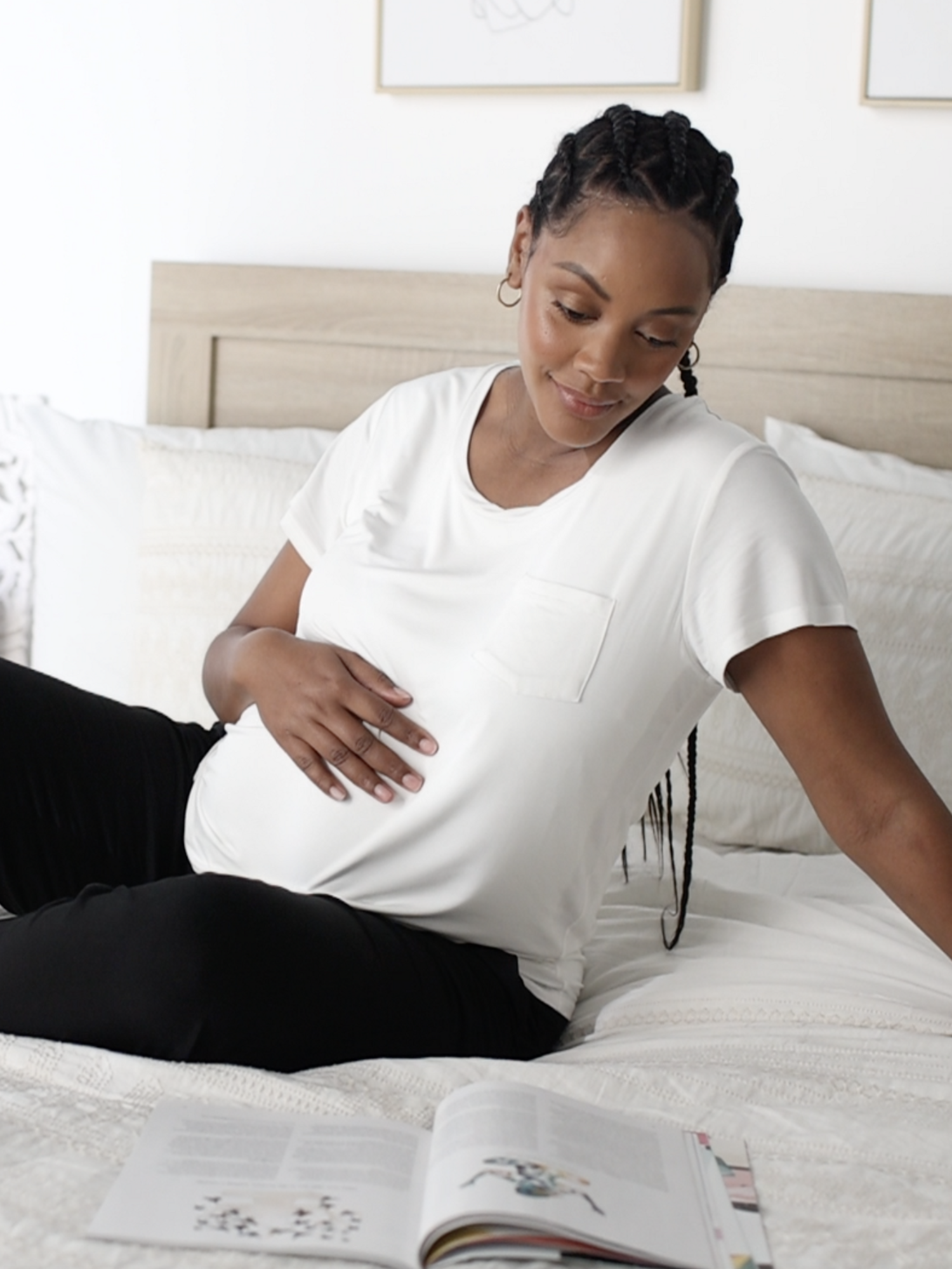 Model sitting on a bed while wearing the Everyday Maternity & Nursing T-shirt in White @model_info:Roxanne is wearing a Large.