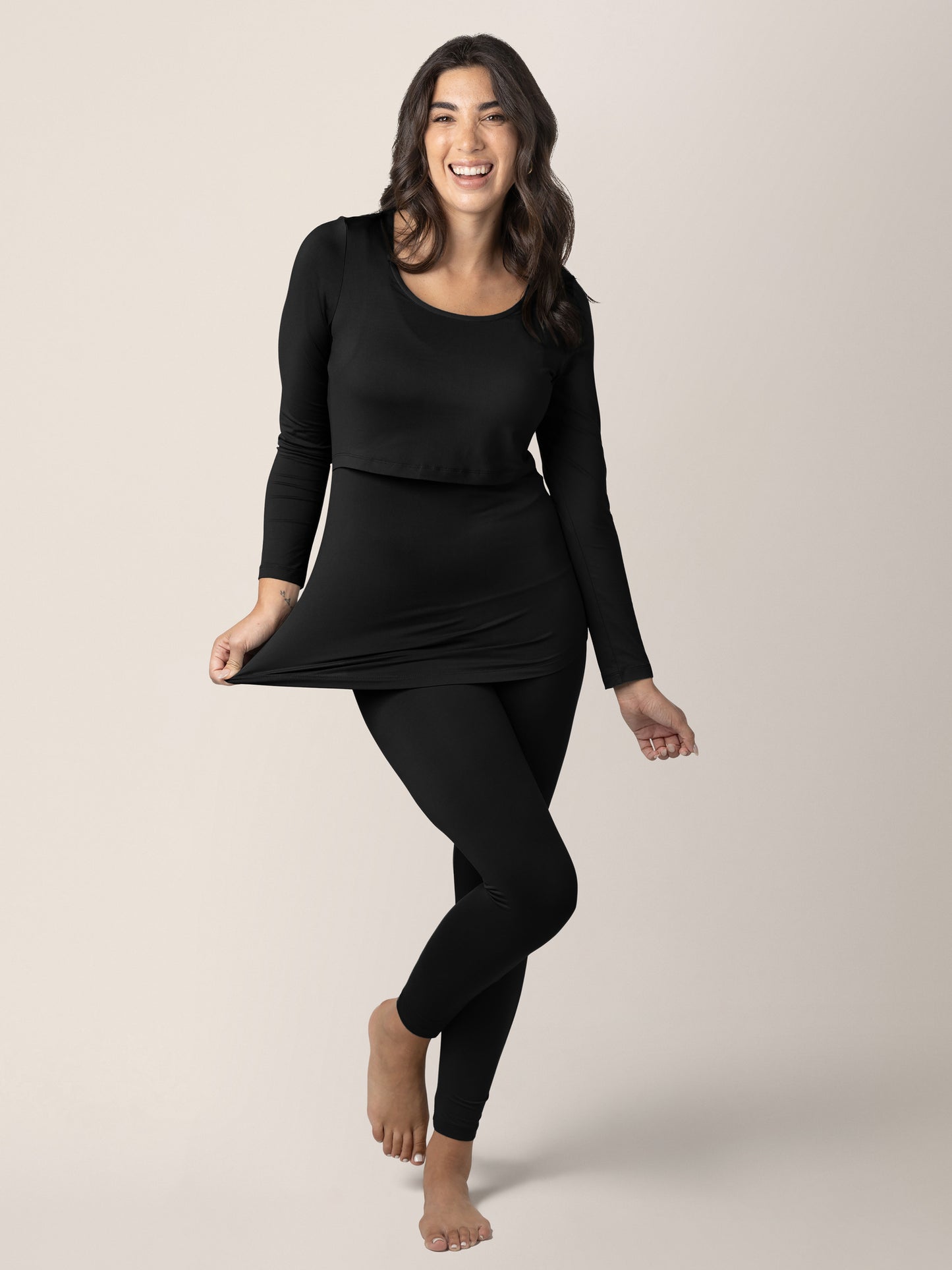 Model wearing the Jane Nursing Pajama Set in Black  with her hand on the hem.@model_info:Alexis is 5'10" and wearing a Medium.