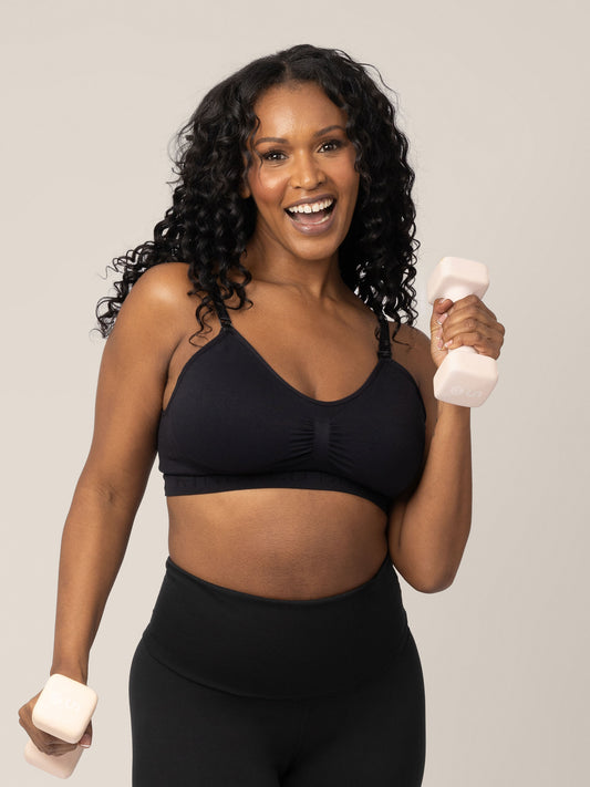 Model wearing the Sublime® Nursing Sports Bra in Black holding two hand weights and exercising. @model_info:Rashé is wearing a Large Regular.