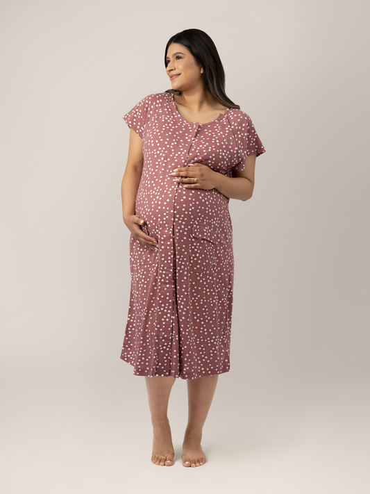 Pregnant model wearing the Universal Labor & Delivery Gown in Rosewood Polka Dot with her hand on her belly. @model_info:Nohely is wearing a S/M/L.