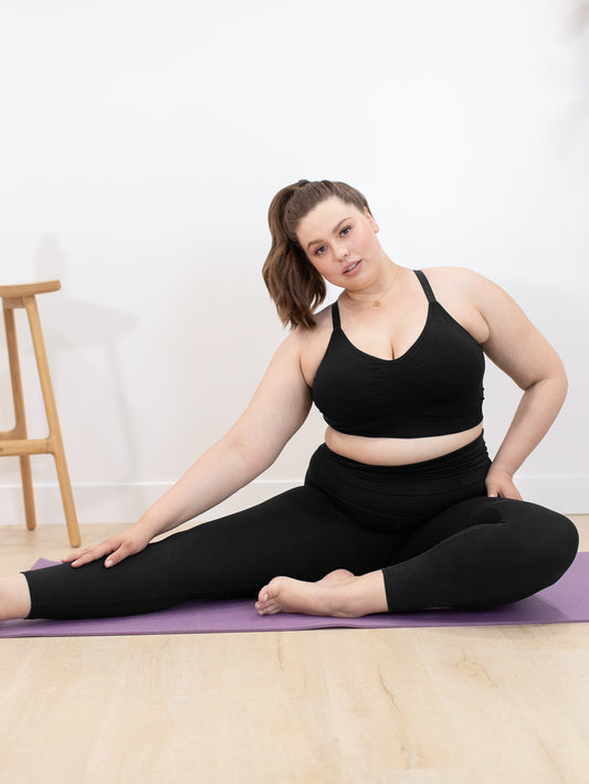 Close-up, athletic girl in black leggings sitting on the floor in