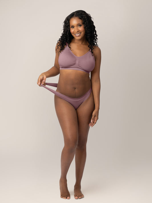 Model wearing the Grow with Me™ Maternity & Postpartum Thong in Twilight holding onto the stretchy waistband on the thong. @model_info:Rashé is wearing a Medium.