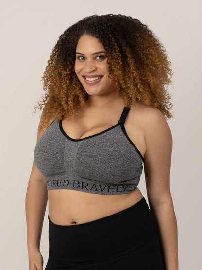 Model wearing the Sublime® Nursing Sports Bra in Heather Grey, smiling at the camera. @model_info:Micah is wearing a Large Busty.