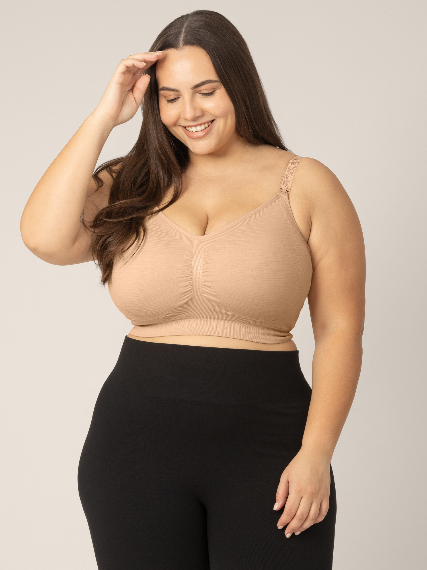 Super-Busty model looking down wearing the Sublime® Hands-Free Pumping & Nursing Bra in Beige.@model_info:Anna is wearing a Large Super Busty.