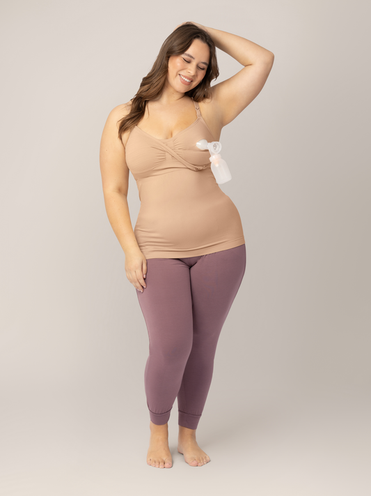 Model wearing the Sublime® Hands-Free Pumping & Nursing Tank in Beige connected to a pump with her hand in her hair.  @model_info:Venezia is wearing a Large Busty.