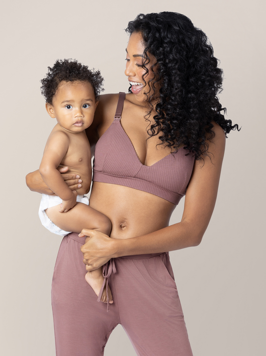 Model holding her baby on her hip while wearing the Ribbed Cotton Maternity & Nursing Bra in Twilight.  @model_info:Anastacia is wearing a Small.