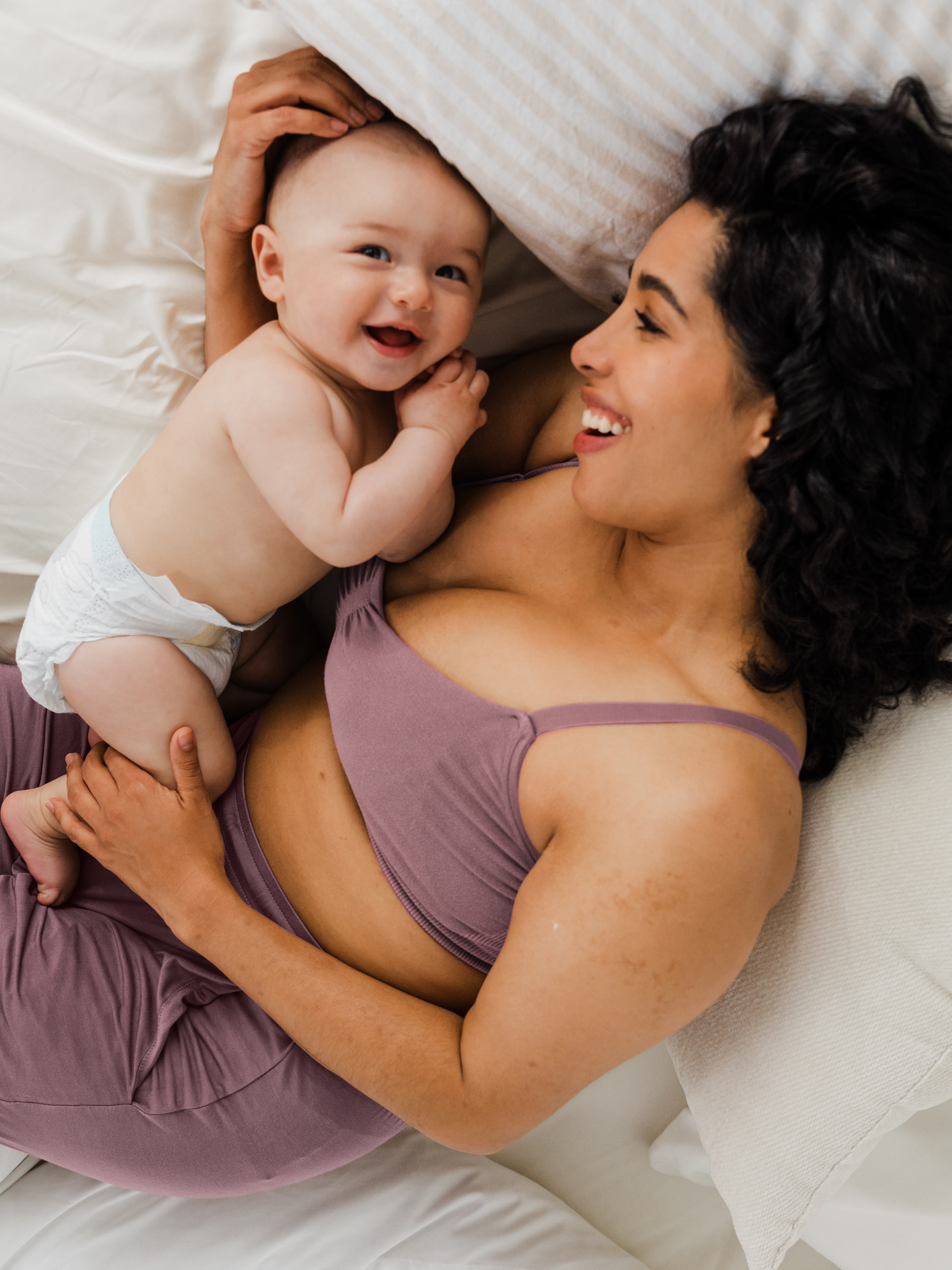 Model laying on the bed with a baby wearing the Sublime® Bamboo Hands-Free Pumping Lounge & Sleep Bra in Twilight 