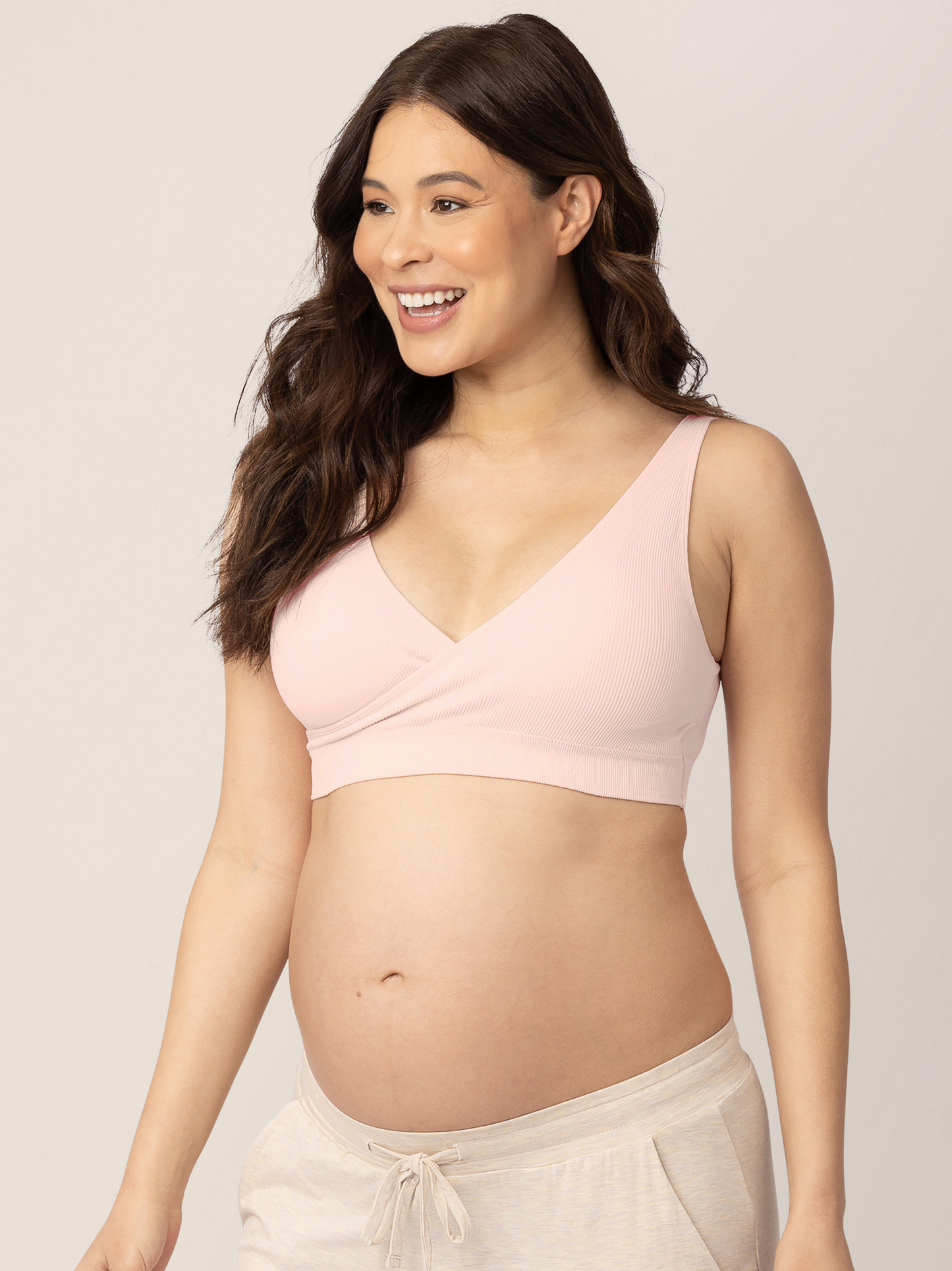 Pregnant model wearing the Sublime® Adjustable Crossover Nursing & Lounge Bra in Soft Pink with her hands at her sides.