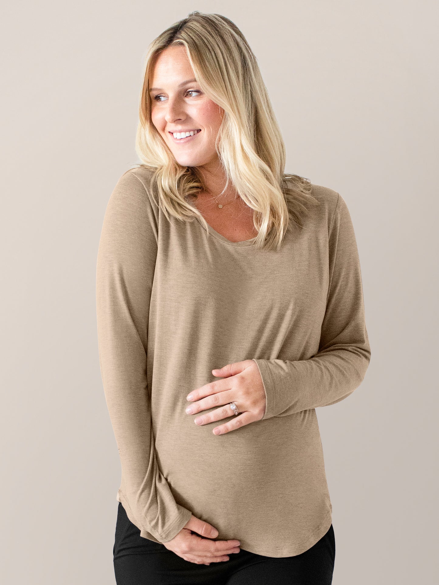Pregnant model wearing the Bamboo Maternity & Nursing Long Sleeve T-shirt in Wheat with her hands on her stomach. @model_info:Maddy is wearing a Small.