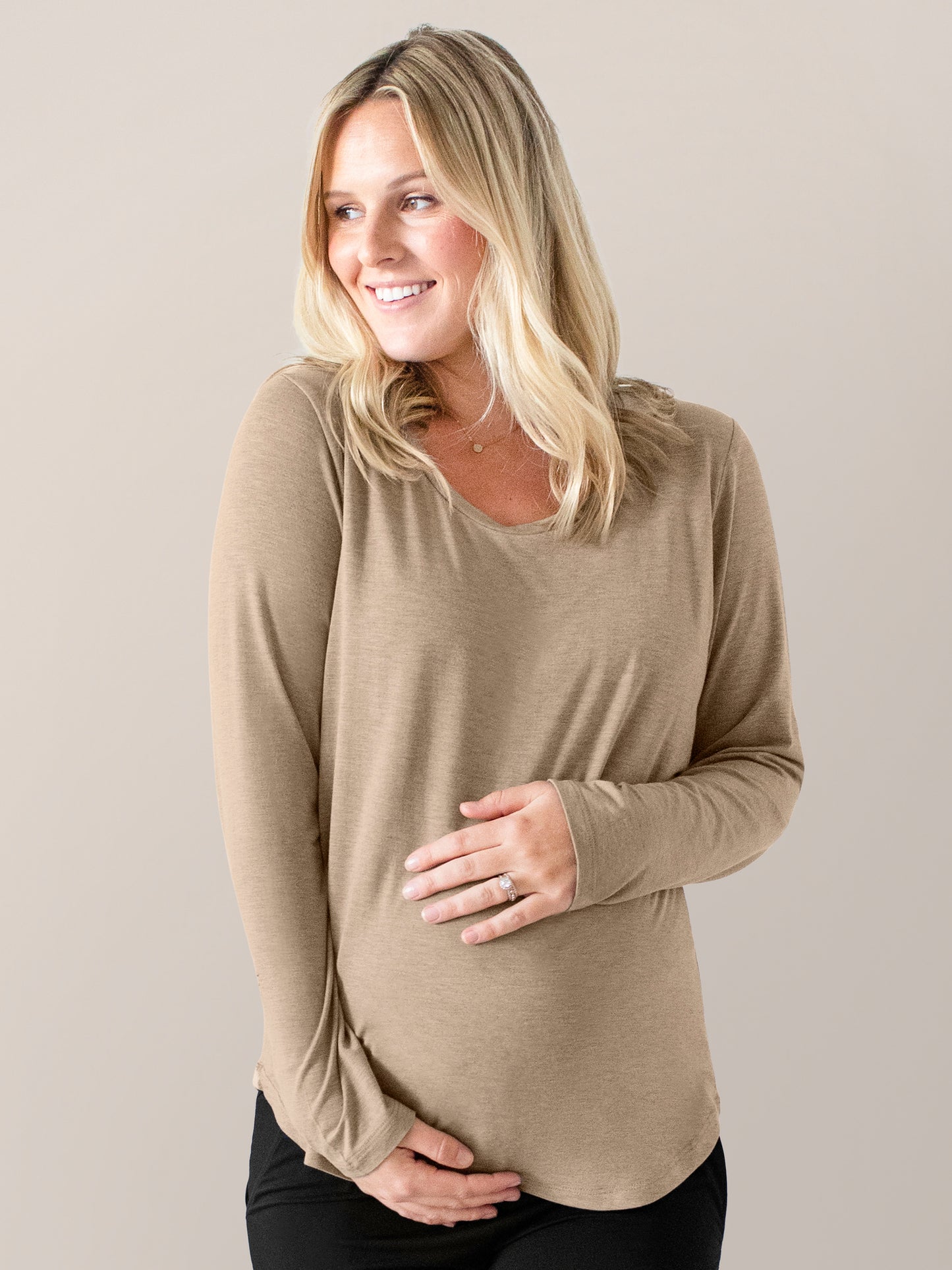 Pregnant model wearing the Bamboo Maternity & Nursing Long Sleeve T-shirt in Wheat with her hands on her stomach. @model_info:Maddy is wearing a Small.