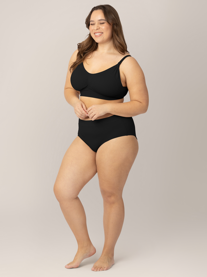 Model wearing the Grow with Me™ Maternity & Postpartum Brief in Black with her hands near her stomach. 