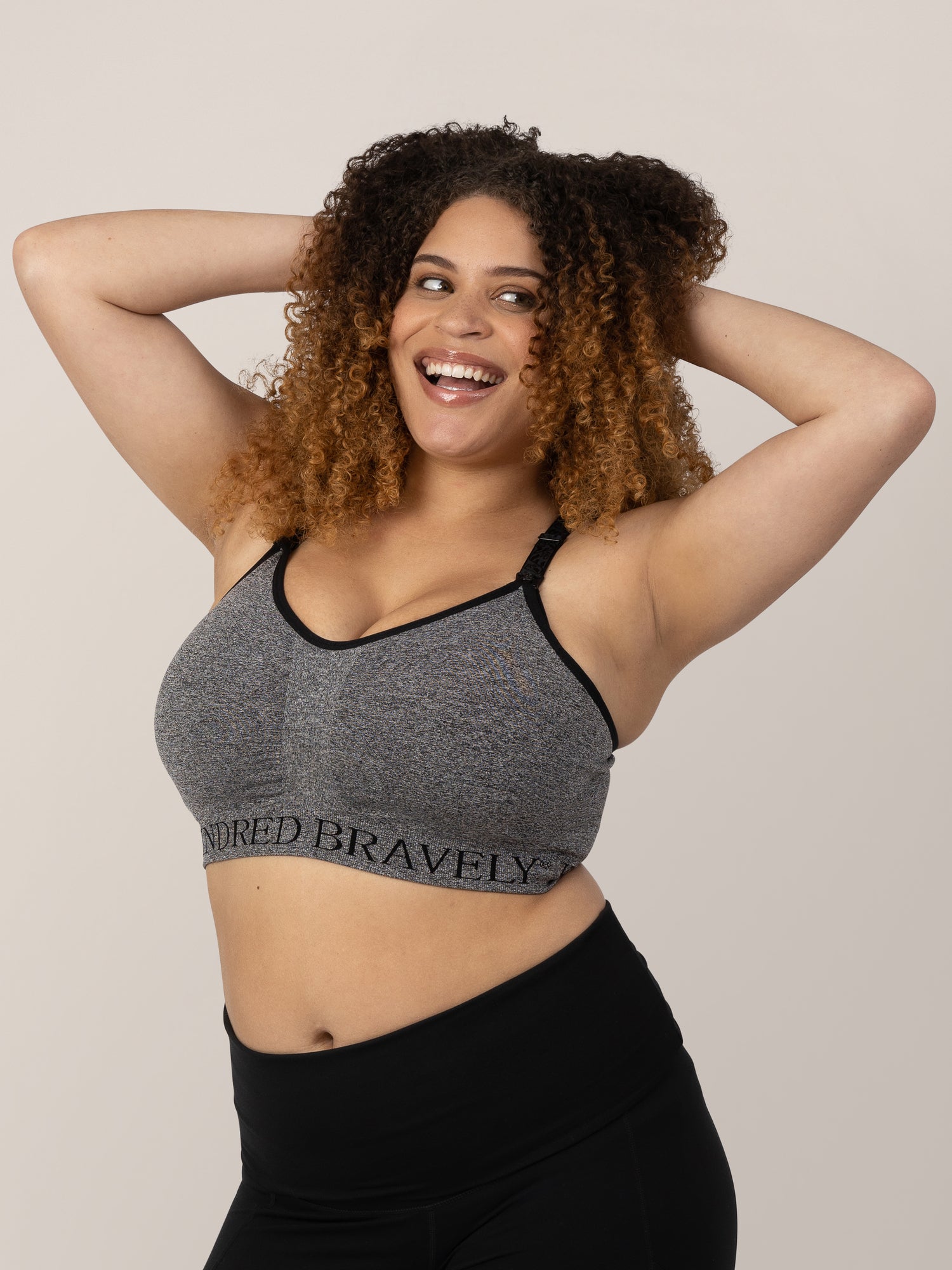 Model wearing the Sublime® Nursing Sports Bra in Heather Grey with her hands on her head.