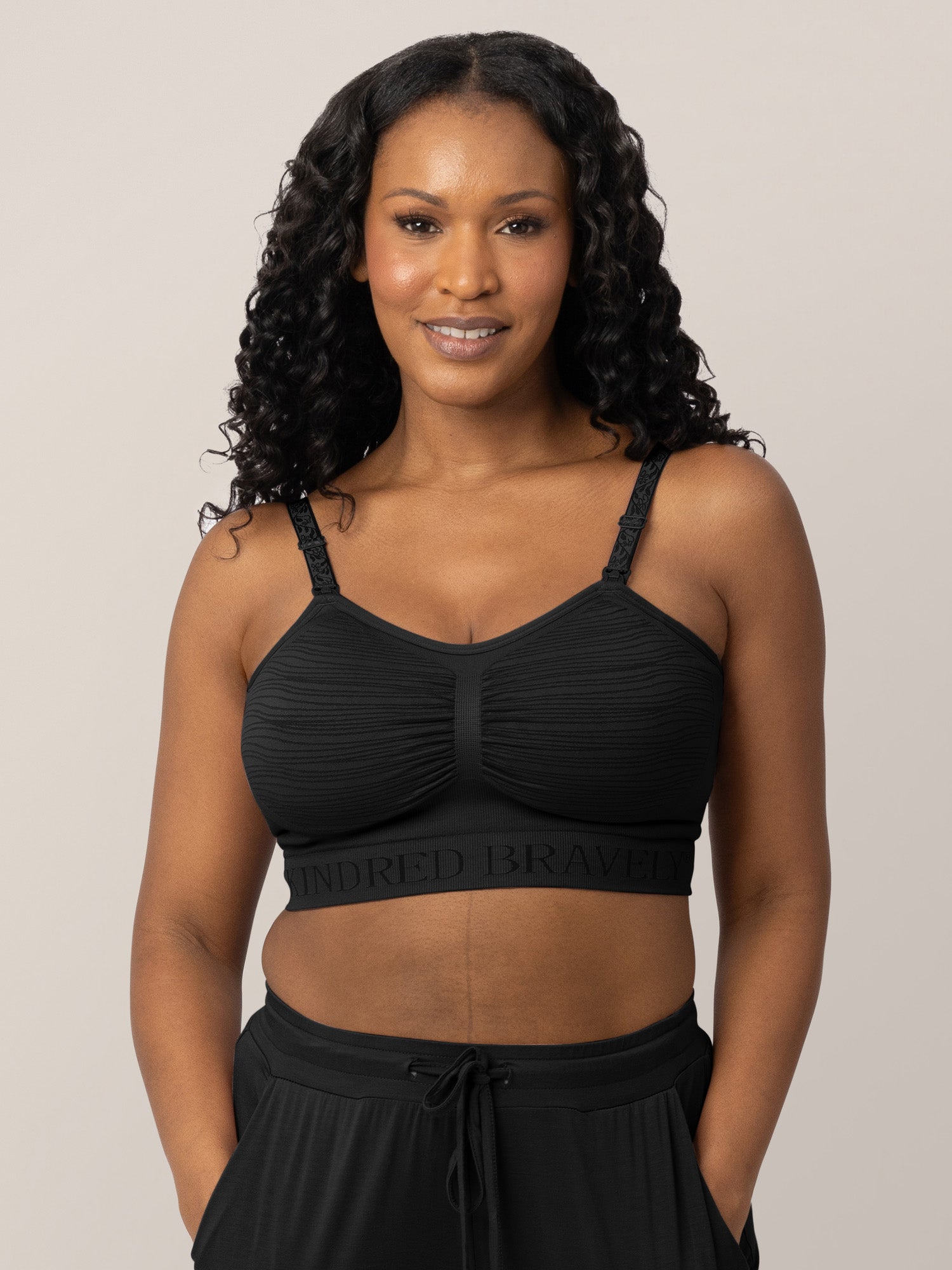 Model wearing the Sublime® Hands-Free Pumping & Nursing Bra in Black with her hands in her pockets.