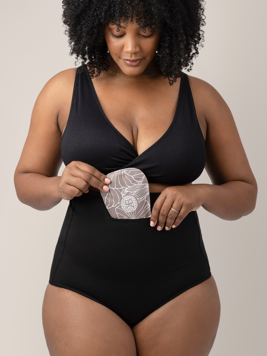 Model wearing the Soothing Fourth Trimester Underwear in Black holding the soothing gel pack insert. @model_info:Roxanne is wearing a Large.