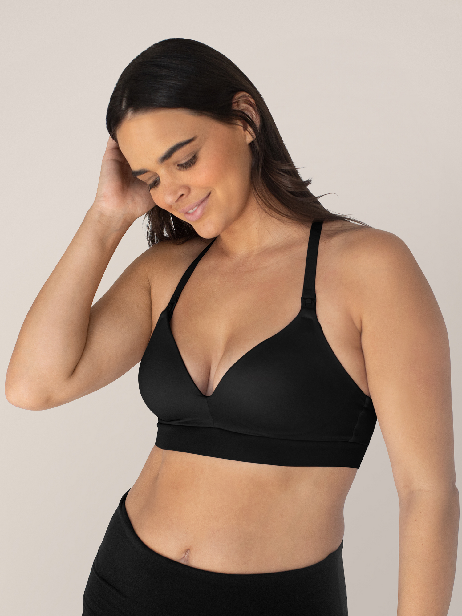 Model wearing the Minimalist Maternity & Nursing Bra in Black looking down at the bottom. @model_info:Brooklyn is wearing a Small.