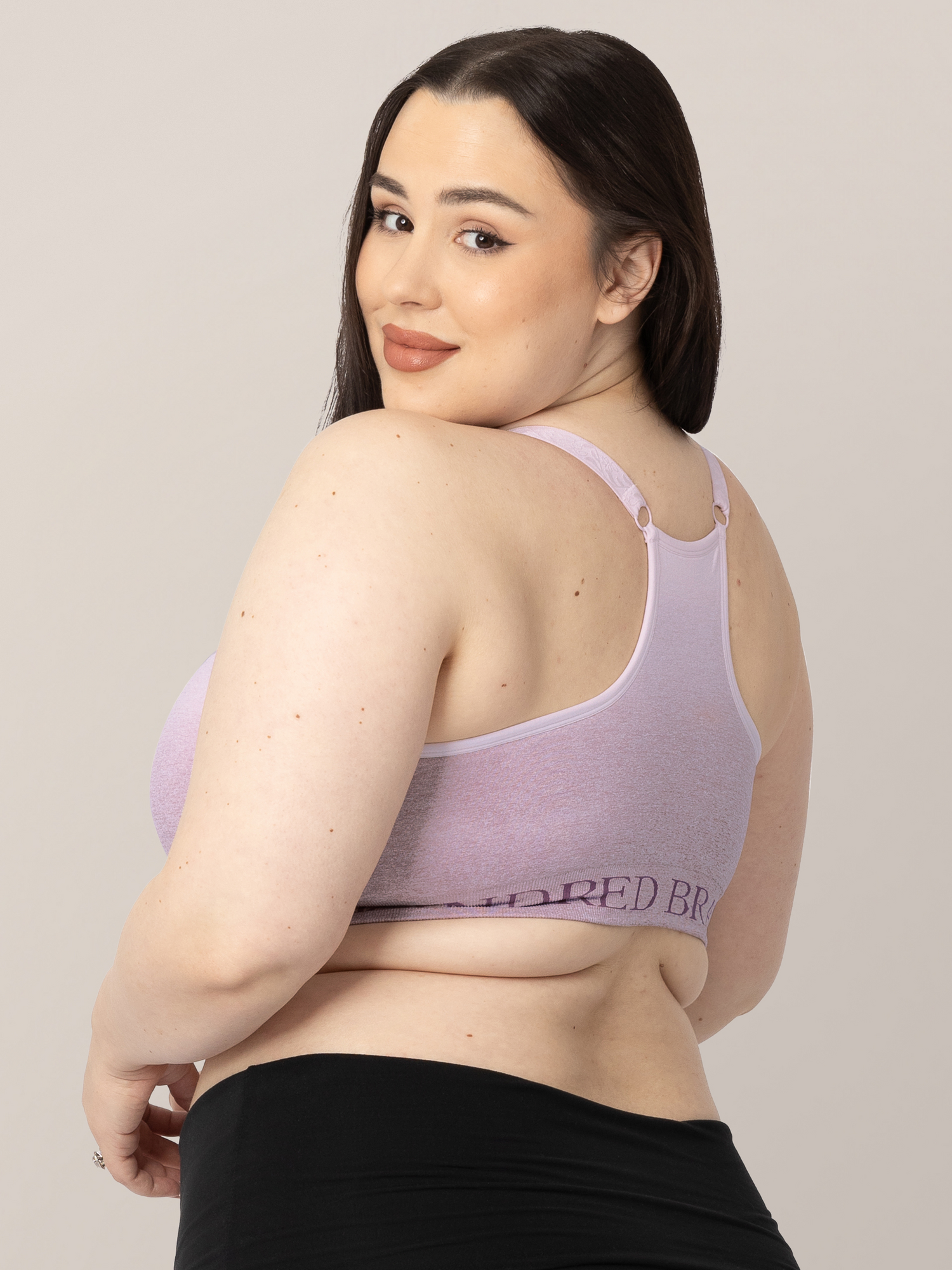 Back of a model wearing the Sublime® Hands-Free Pumping & Nursing Sports Bra  in Ombre Purple looking over her shoulder.