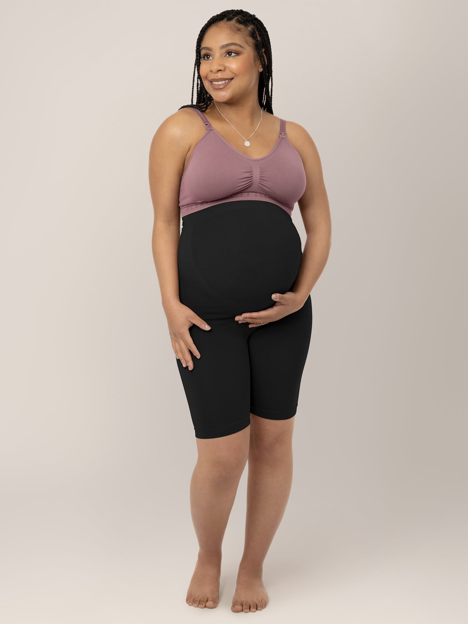 Model holding her belly while wearing the Seamless Bamboo Maternity Thigh Savers in Black