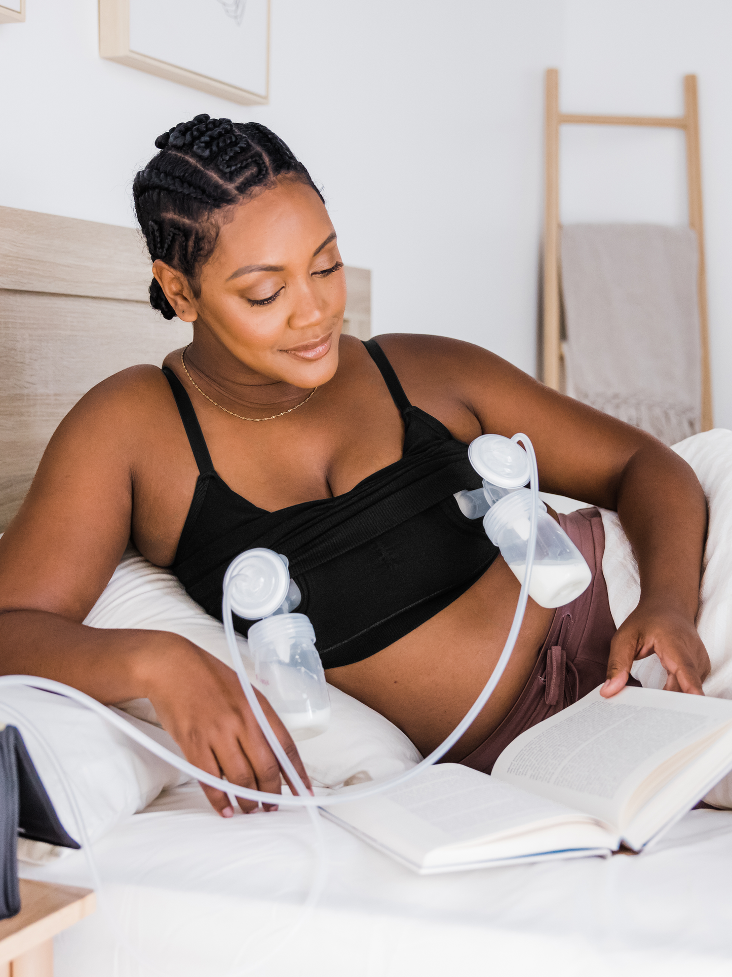 Model is laying on a bed while pumping and wearing the Sublime® Bamboo Hands-Free Pumping Lounge & Sleep Bra in Black.