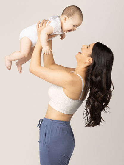 Model holding her baby up in the air while wearing the Sublime® Bamboo Hands-Free Pumping Lounge & Sleep Bra in Oatmeal Heather