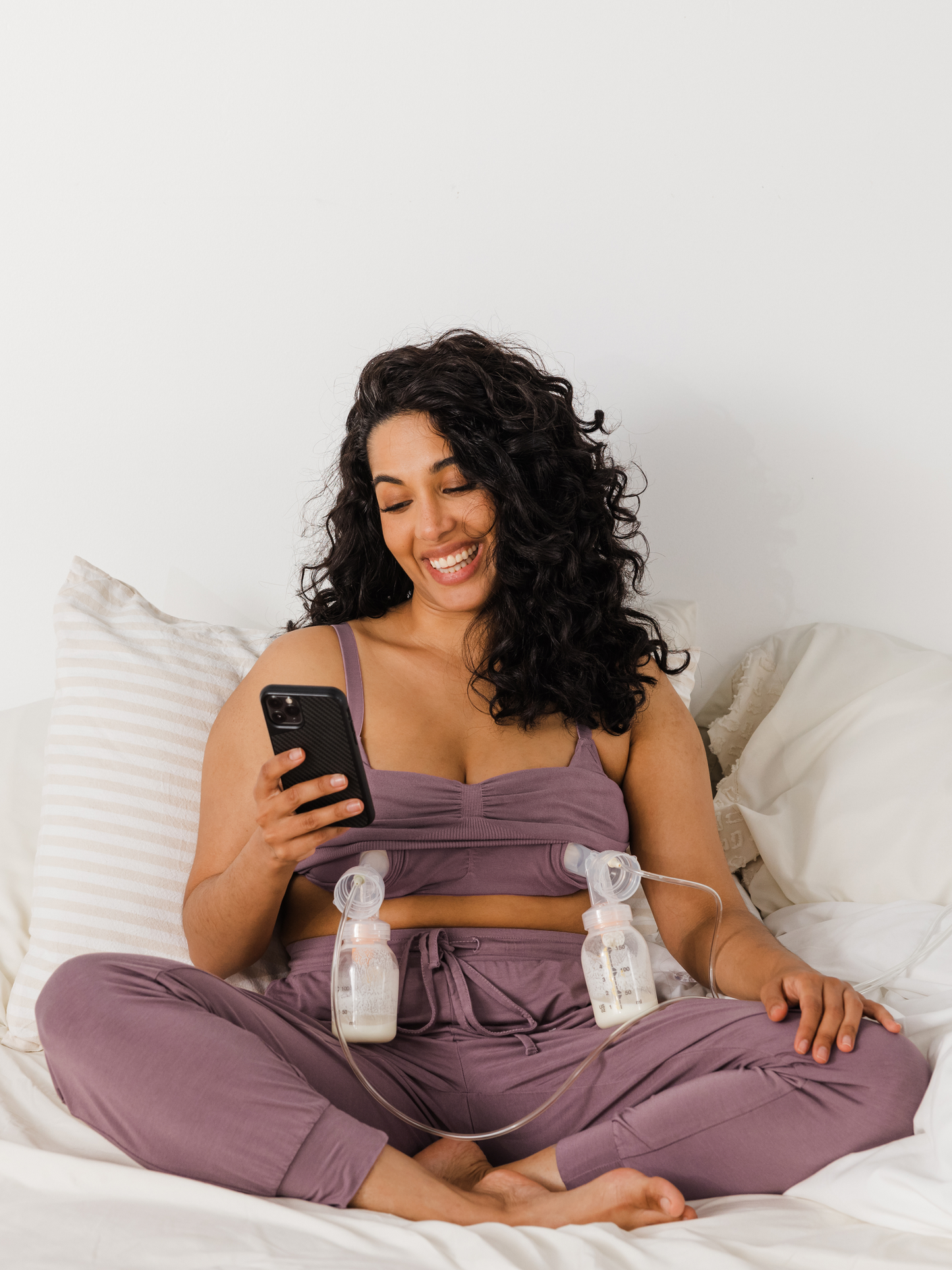 Model sitting on a bed pumping while wearing the Sublime® Bamboo Hands-Free Pumping Lounge & Sleep Bra in Twilight  