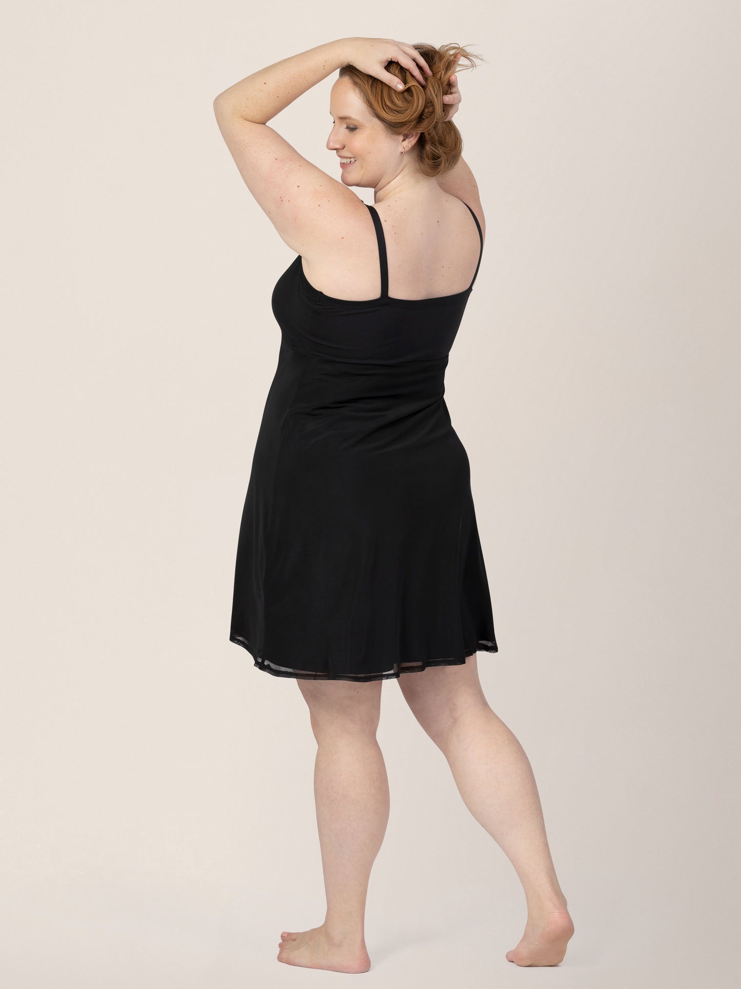 Angled back view of model wearing the Aurora Mesh Nursing Nightgown in black, holding hair up.