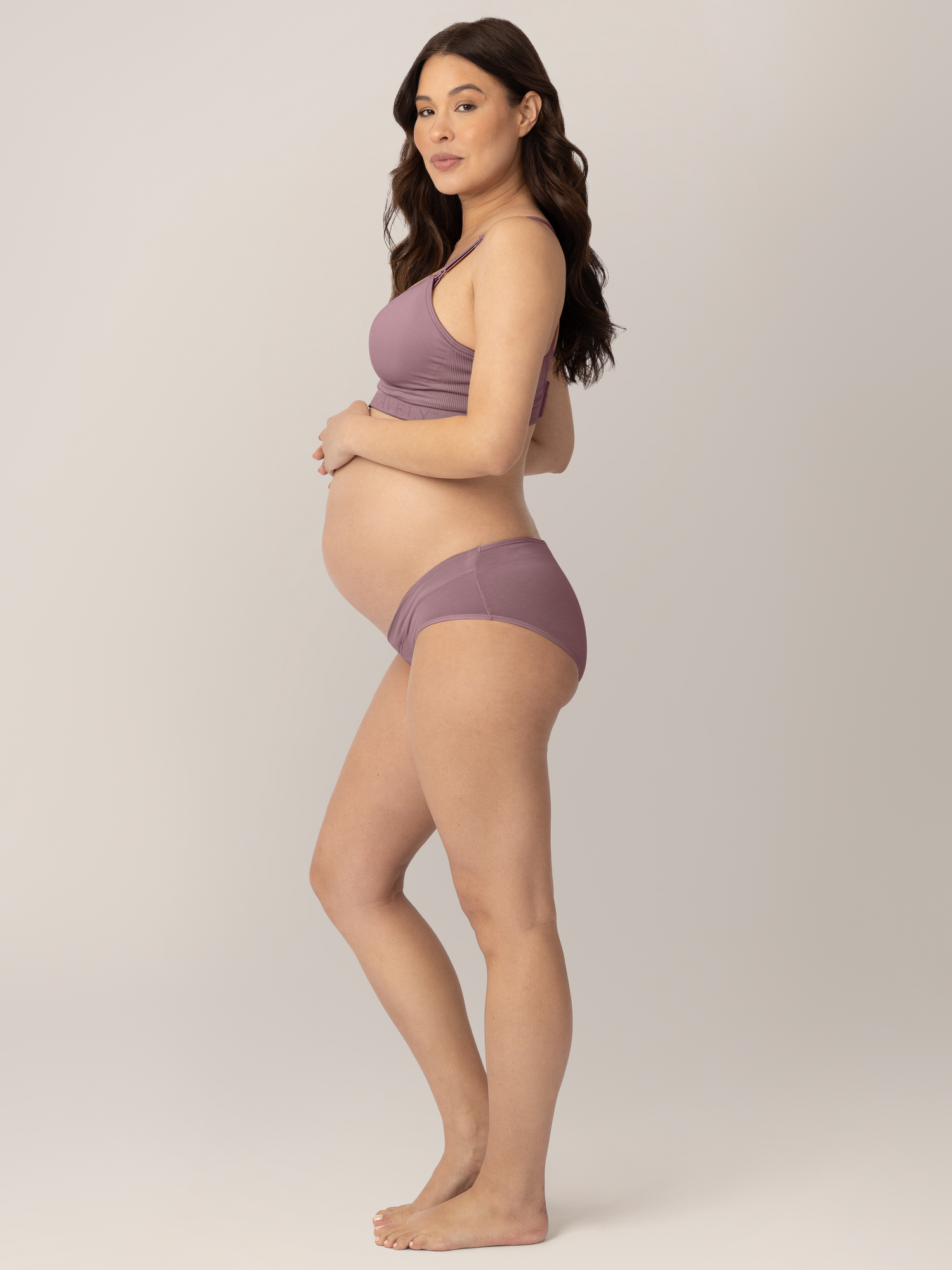 Side view of a pregnant model wearing the Under-the-Bump Bikini Underwear in assorted colors 