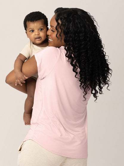 Back of a model wearing the  Everyday Maternity & Nursing T-shirt in Dusty Pink holding her baby.