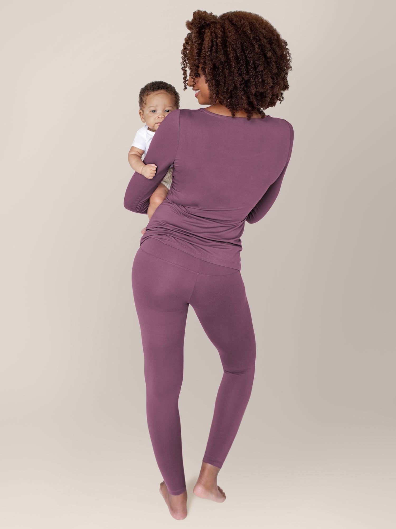 Model holding her baby on her hip wearing the Jane Nursing Pajama Set in Burgundy Plum.