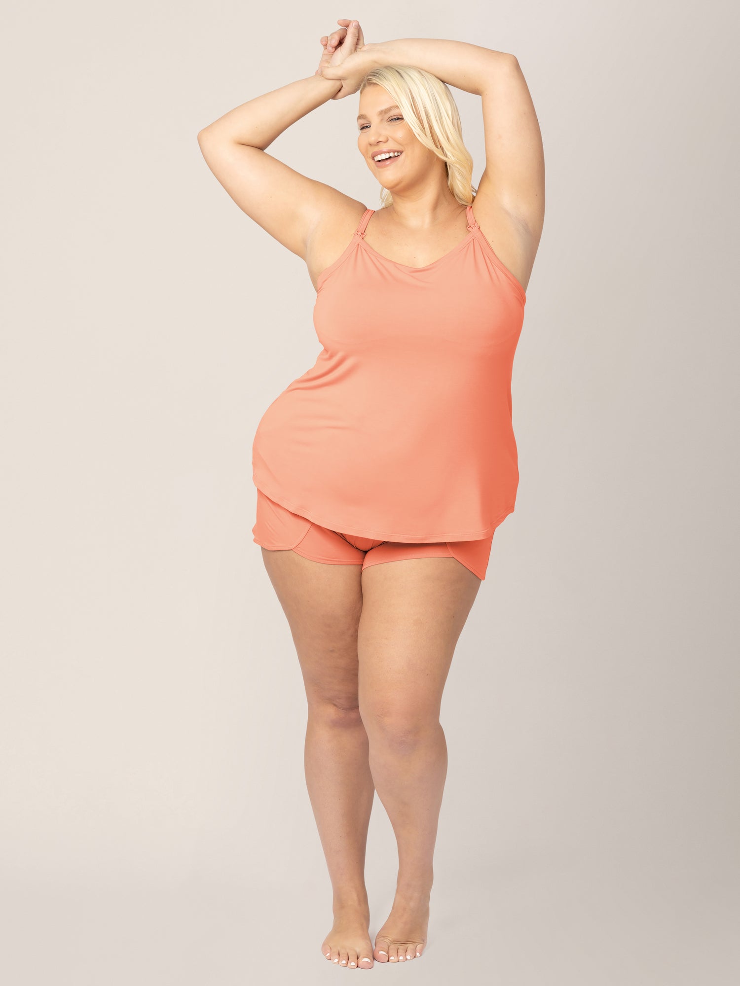 Front view of model wearing the Bamboo Lounge Around Nursing & Maternity Tank in vintage coral paired with matching Bamboo Maternity & Postpartum Lounge Shorts with her hands above her head.