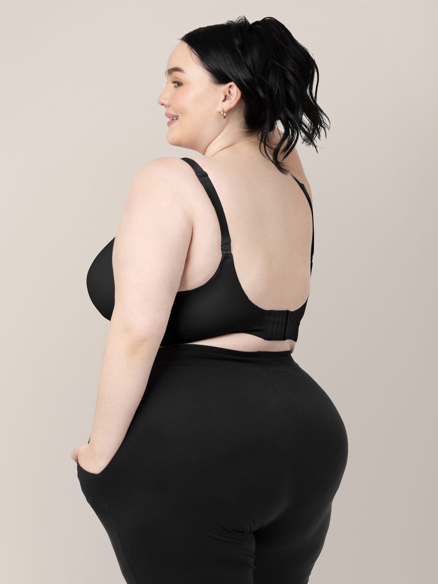 Back of a model wearing the Minimalist Maternity & Nursing Bra in Black with her hands in her hair. 