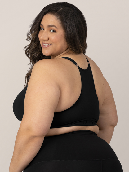 Back view of a model wearing the Sublime® Hands-Free Pumping & Nursing Sports Bra in Black with her hands at her sides.